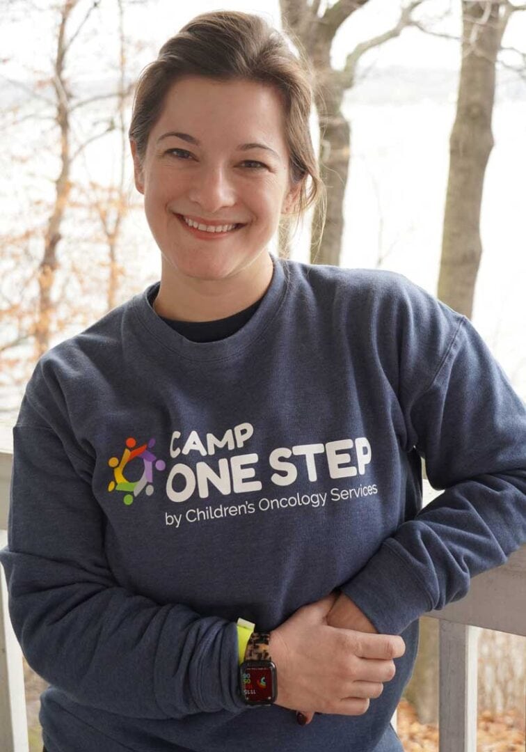 Camp One Step Children's Oncology Services charity event, outdoor setting with smiling volunteer woman.