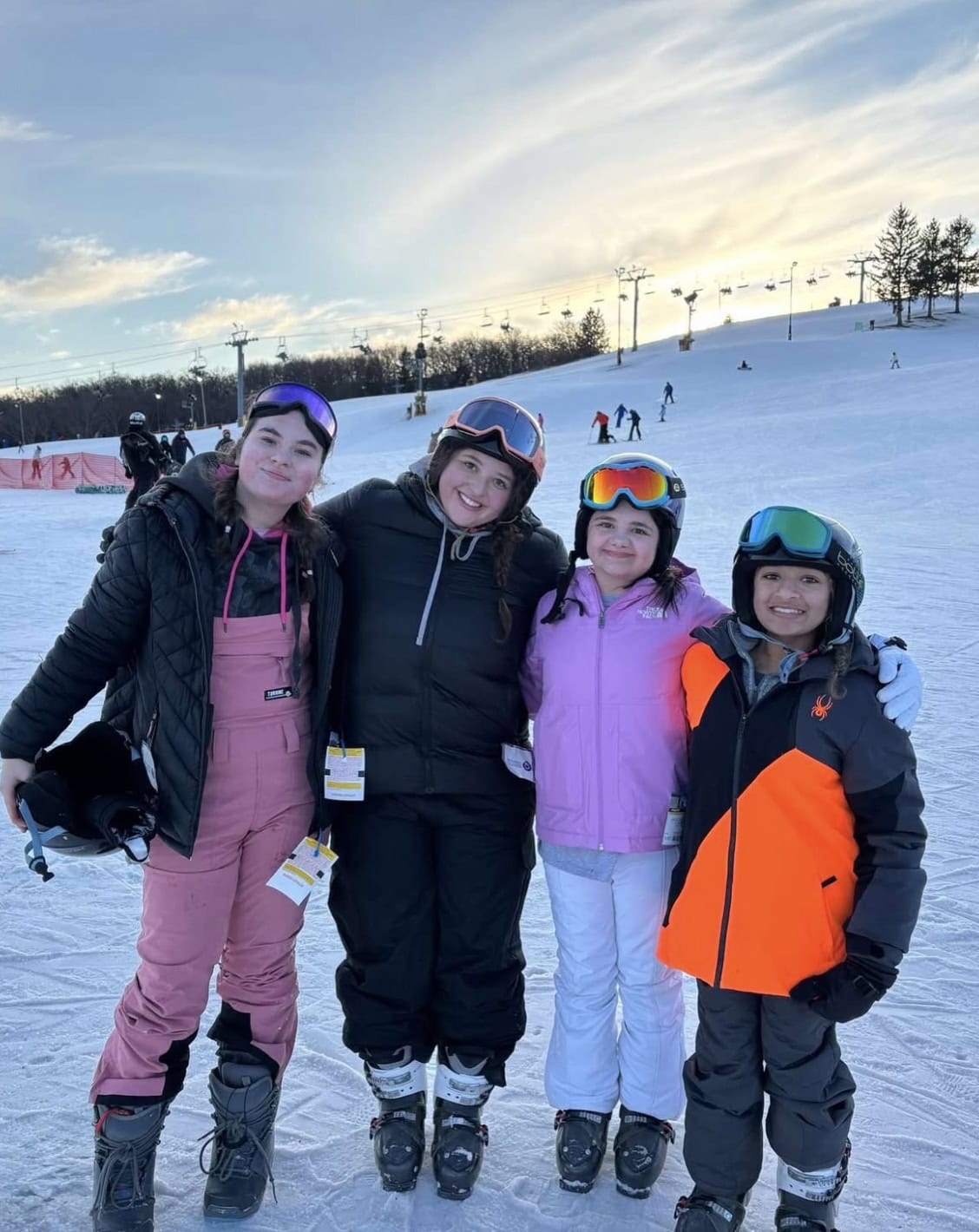 Young skiers wearing helmets and gear smiling at Camp One Step ski camp.
