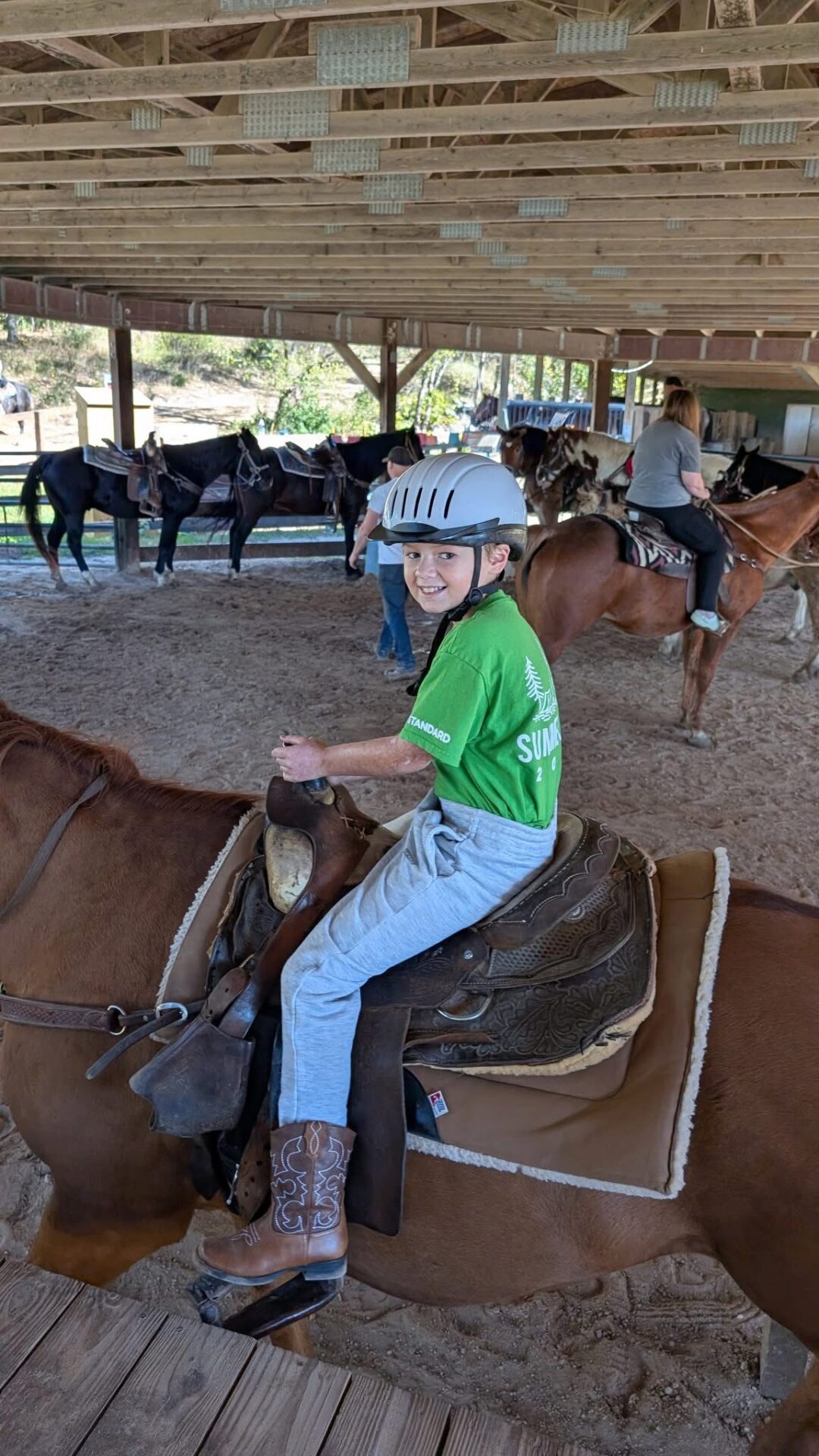 Young rider enjoying horse riding experience with safety gear.