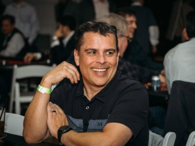 Motivated man smiling at Camp One Step charity event for children with cancer.