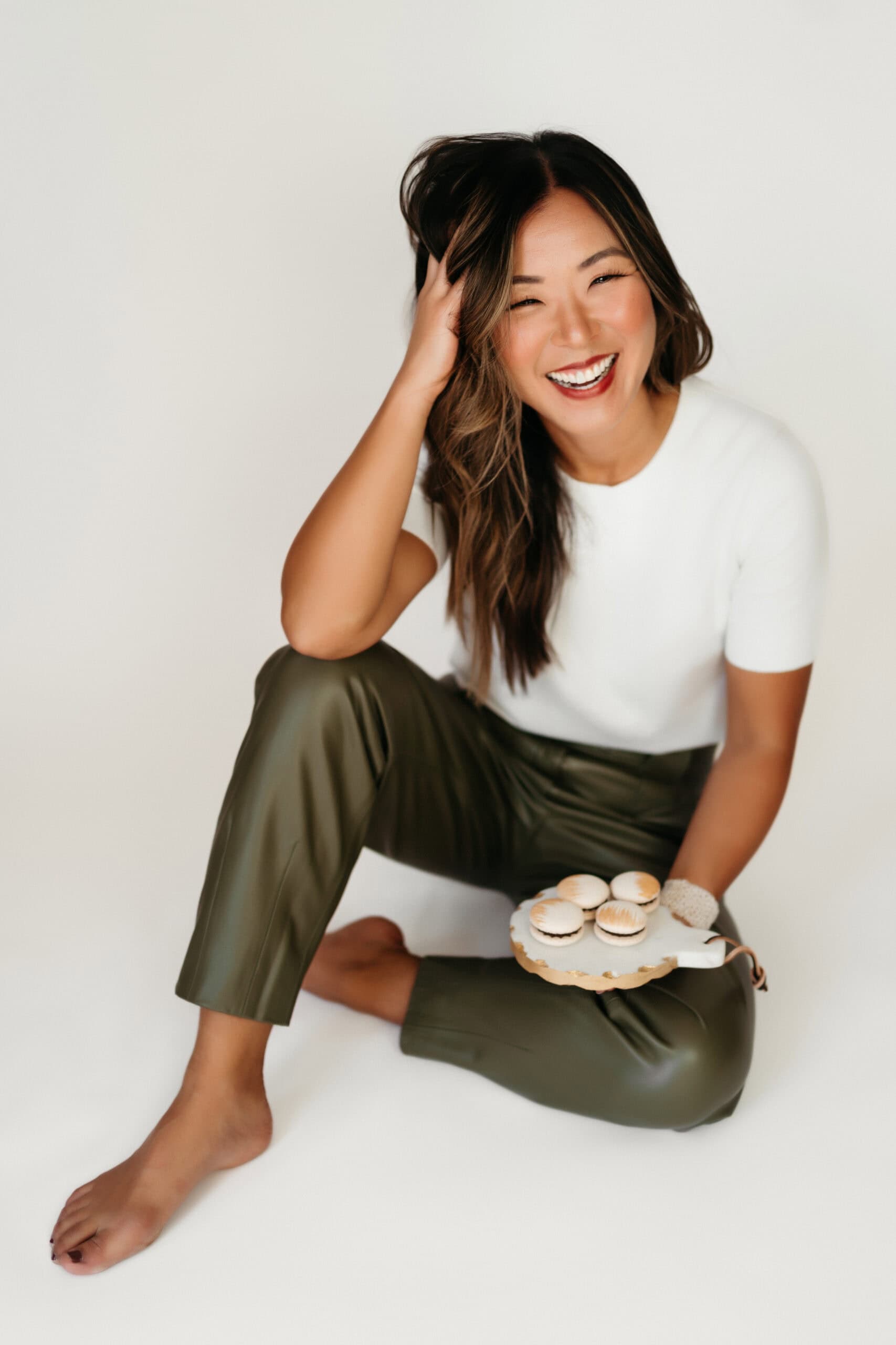 Smiling woman holding macarons on white background