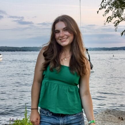 Beautiful young woman smiling by the lake at Camp One Step, summer camp activities and outdoor fun.