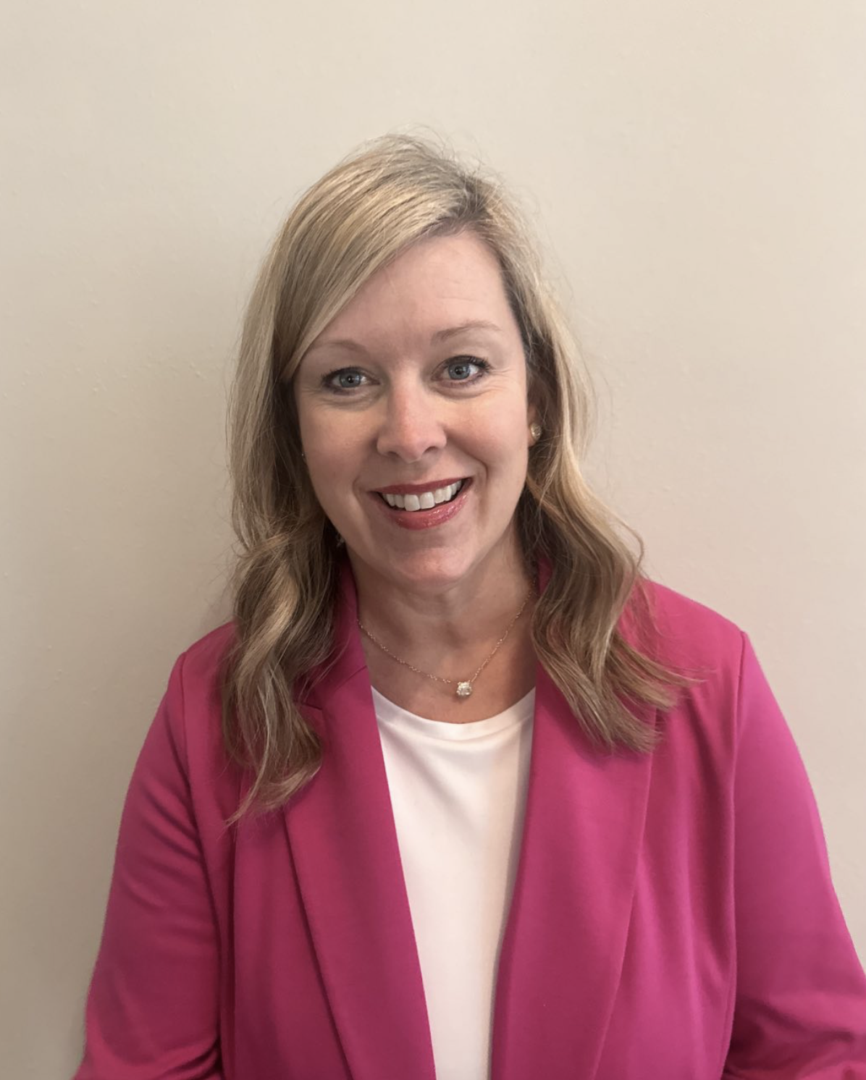 Smiling woman in a pink blazer.