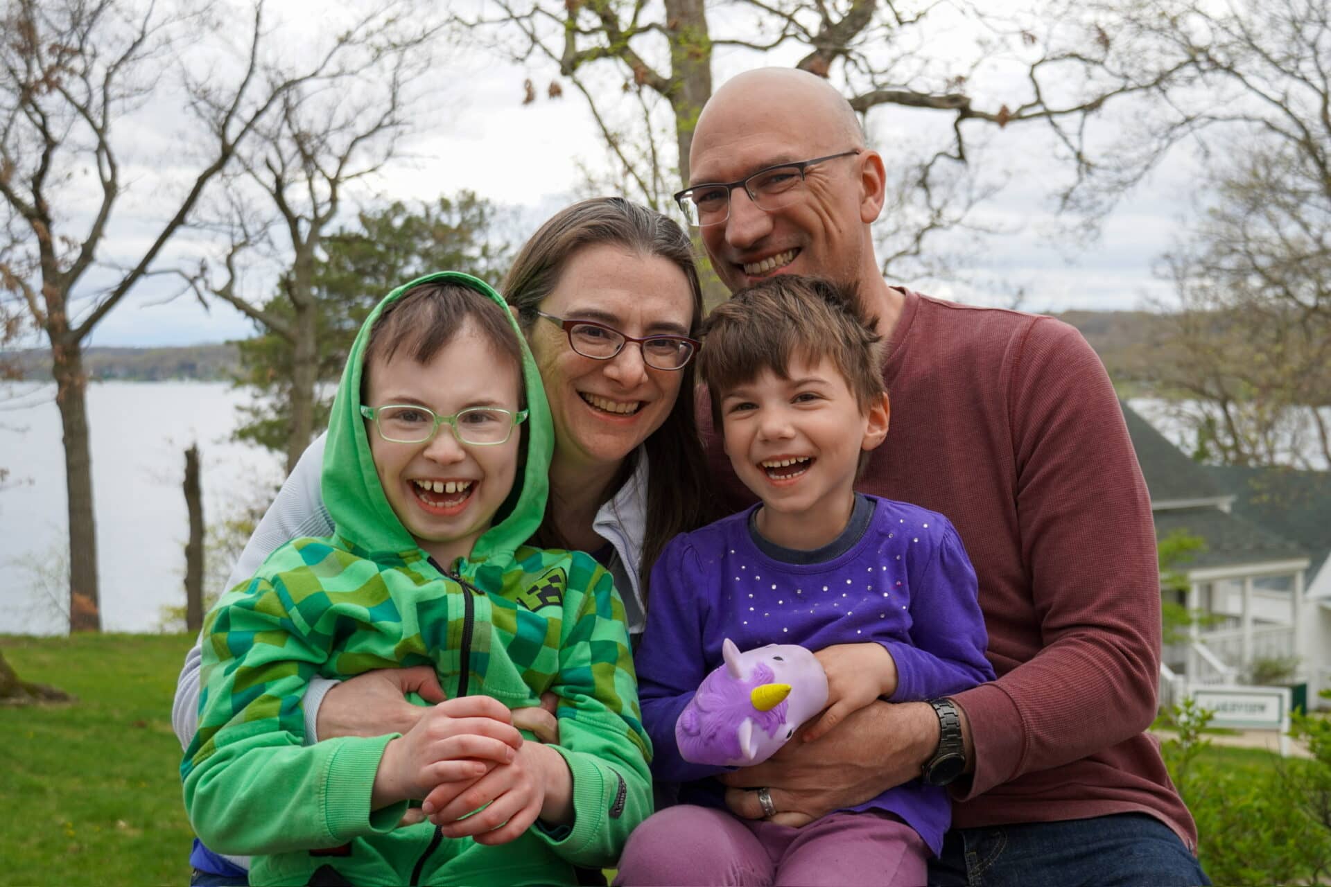 Happy family enjoying a day outdoors with kids and a colorful plush unicorn toy.