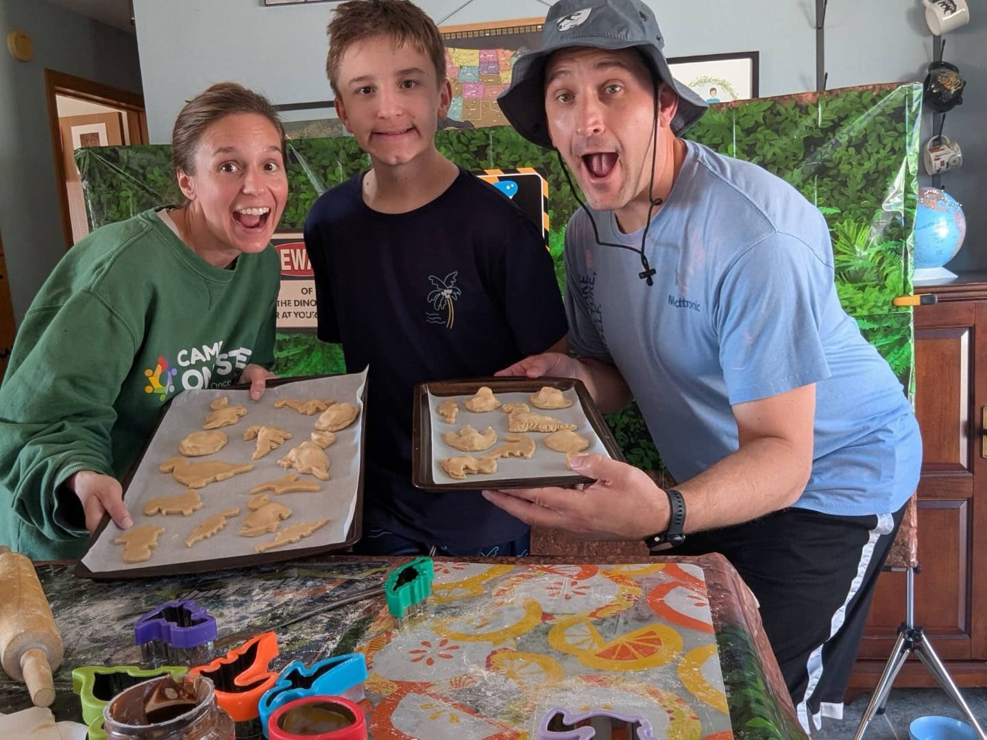 1. Smiling family baking dinosaur-shaped cookies at Camp One Step, outdoor fun with kids.