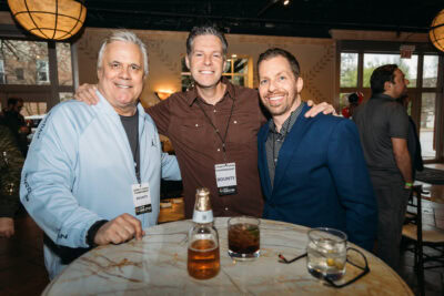 Smiling men at a networking event enjoying drinks at Camp One Step conference.