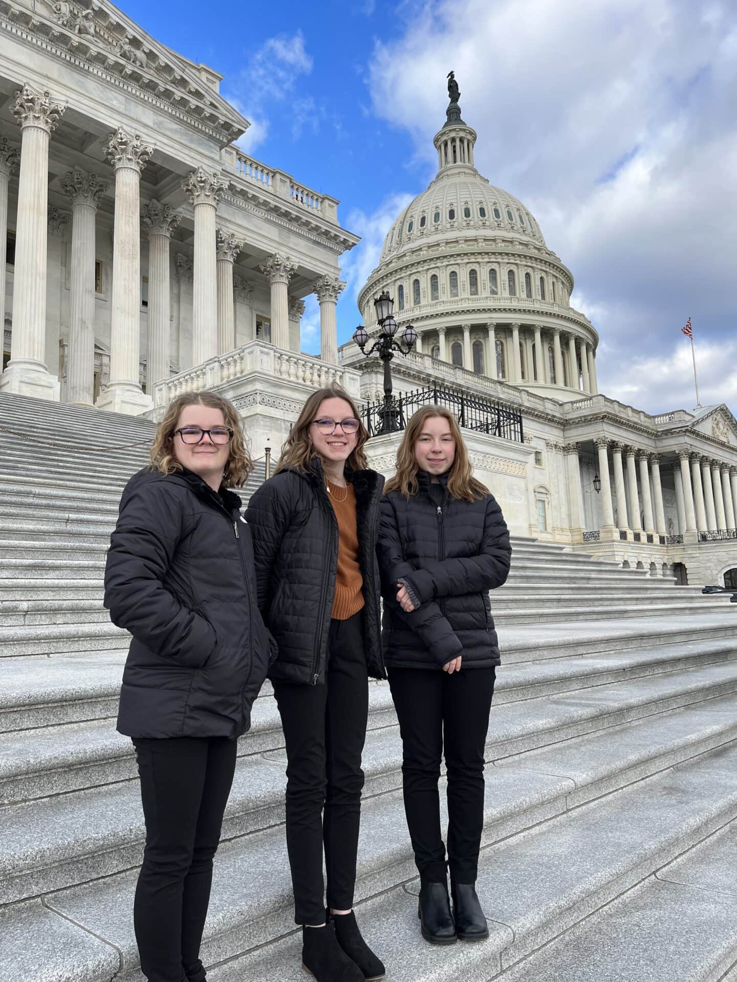 Children standing on the steps of the U.S. Capitol with iconic architecture in the background.