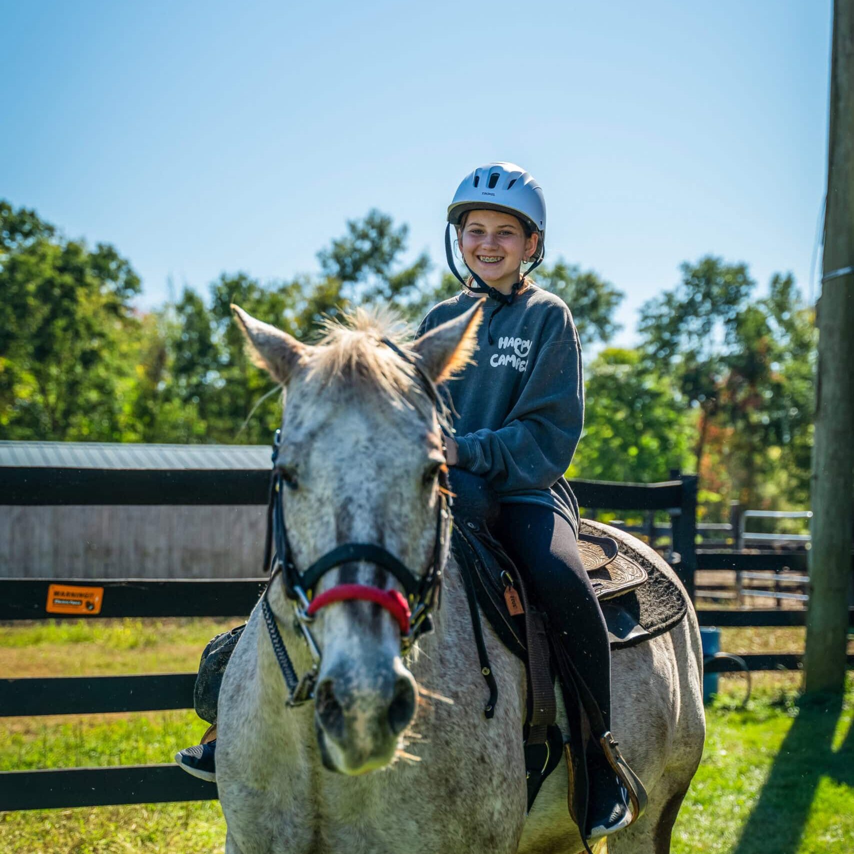Young girl smiling while horseback riding at Camp One Step adventure camp.