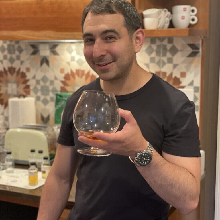 Relaxed man enjoying a drink at Camp One Step in a cozy kitchen setting.