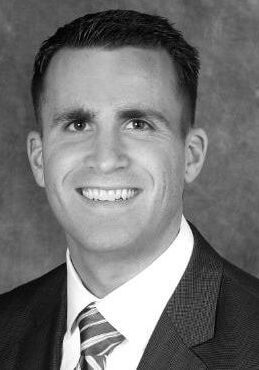 Black and white professional headshot of smiling man