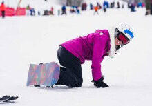 - Girl kneeling in snow with snowboard, winter sports, Camp One Step.