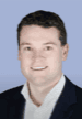 Professional headshot of man in suit smiling