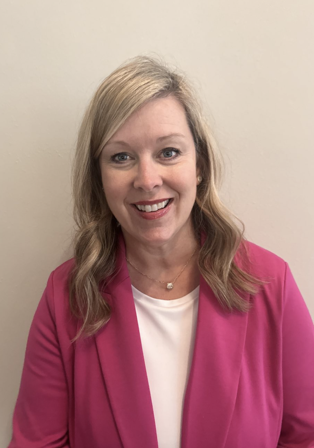 Smiling woman in a pink blazer.