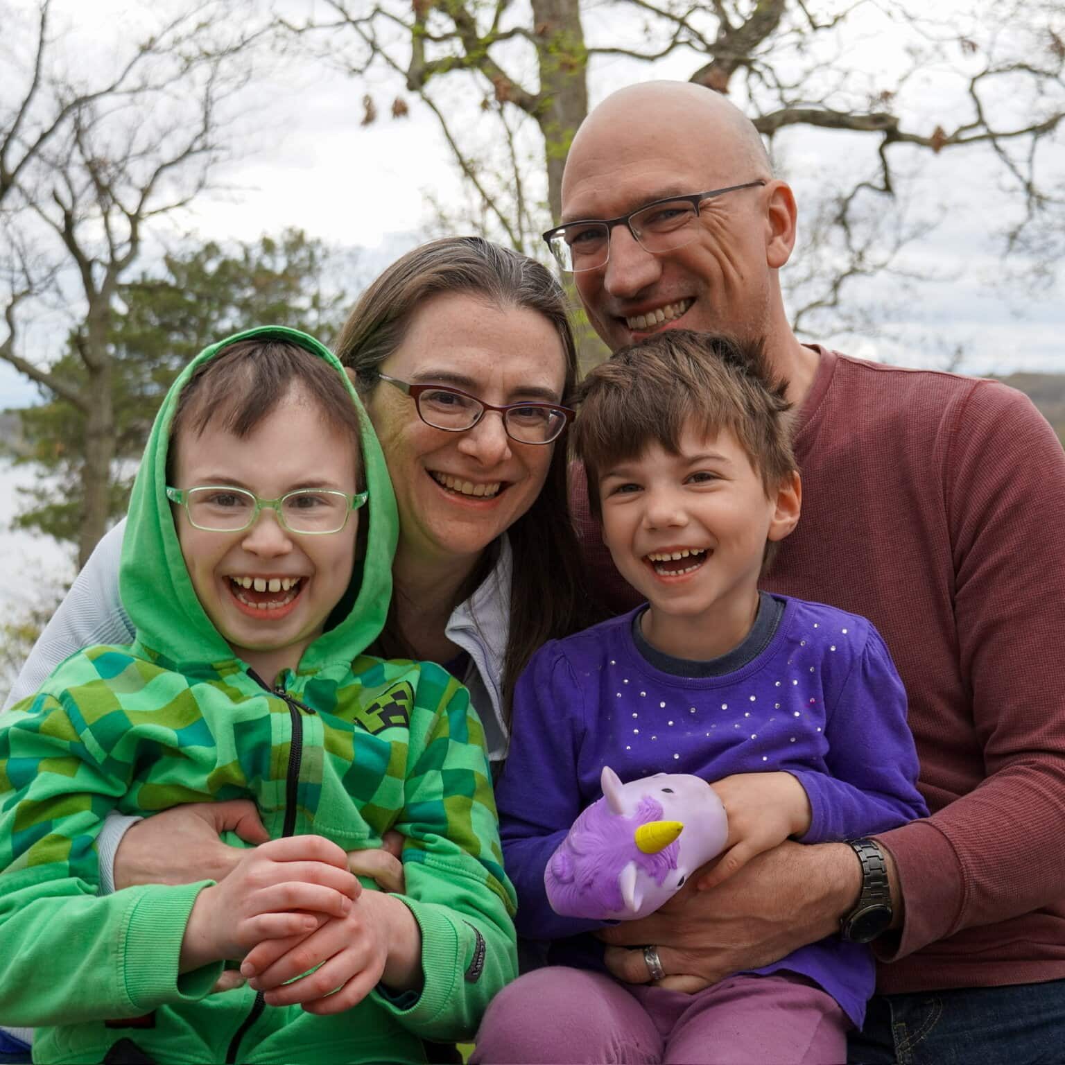 Happy family enjoying a day outdoors with kids and a colorful plush unicorn toy.