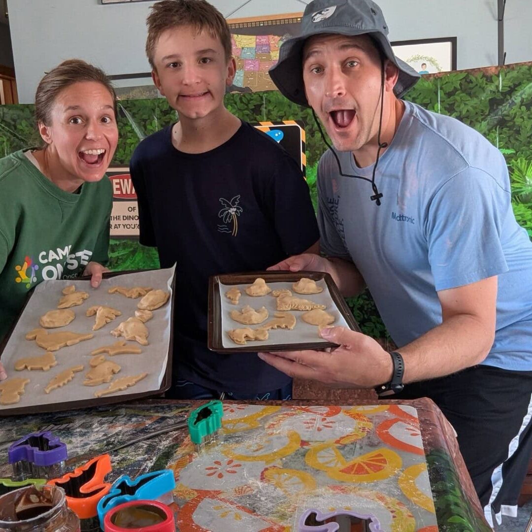 1. Smiling family baking dinosaur-shaped cookies at Camp One Step, outdoor fun with kids.